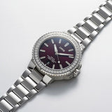 Three-quarter angle view of the Oris Aquis Date Relief 41.50cmm Automatic Watch 733 7766 4998MB, highlighting the diamond-set case and domed sapphire crystal. The red dial and date window are visible from this angle.