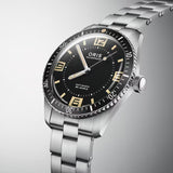 Three-quarter angle view of the Oris Sixty Five Automatic Men's 40mm Watch 733 7772 4034SET, highlighting the bi-directional rotating bezel and domed sapphire crystal. The black dial and vintage-style numerals are visible from this angle.