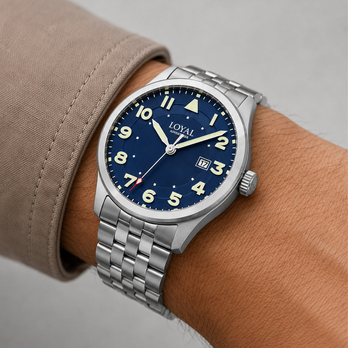 The Loyal Adventurer Pilot Watch worn on the wrist, showing the true scale of the 40mm case and blue dial. The stainless steel finish and 12 o'clock orientation triangle give this quartz watch a distinctive, versatile look for daily wear, alongside the bonus blue leather strap included with this set.