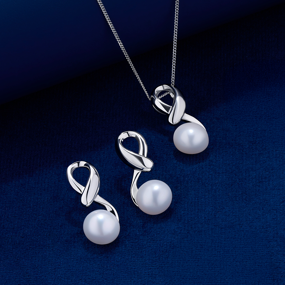 The Wallace Bishop Pearl & Sterling Silver Pendant and Earrings Set, reference 33PSET006, laid out on a deep blue velvet surface. The pendant hangs from a fine chain and each earring has a polished silver twist design with a round white pearl at the base.