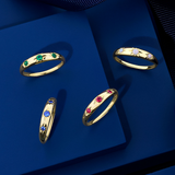 Front-on view of four Wallace Bishop Starburst Rings in 9ct Yellow Gold, each with three round gemstones in star hammer settings across a tapered band that narrows from 4mm to 2mm: the Opal Starburst Ring, reference 36RGSBOYO, the Created Emerald Starburst Ring, reference 38RGSBEYO, the Created Ruby Starburst Ring, reference 38RGSBRYO, and the Created Sapphire Starburst Ring, reference 38RGSBSYO.