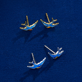 The Wallace Bishop Bluebird of Happiness Stud Earrings in 9ct Yellow Gold, reference 39BB06, measuring 12 x 7.70mm, shown together with the Bluebird of Happiness Stud Earrings in Sterling Silver, reference 49SBB02. Both pairs are bird-shaped studs finished in blue enamel, one in warm yellow gold and one in bright silver.