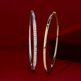 Front-on view of two Wallace Bishop diamond bangles: the 0.15 TDW Hammerset Diamond Bangle in 9ct Yellow Gold, reference 3BHSB01Y, and the 0.50 TW Diamond Bangle in 9ct White Gold, reference 3BG050DW.