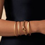 Solid round bangle in 9ct yellow gold featuring a classic polished design with a 4mm width and 65mm size displayed with three other gold bracelets