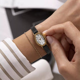 A gold Timex watch with a white dial and leather strap on a wrist