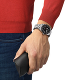 Man Wearing A Tissot PRS 516 Men's Automatic Watch with a stainless steel band and a black dial.