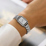 Timex Vivienne women’s watch with white Roman numeral dial, silver-tone bracelet, and petite rectangular silver-tone case in an elegant vintage-inspired dress watch design - on wrist