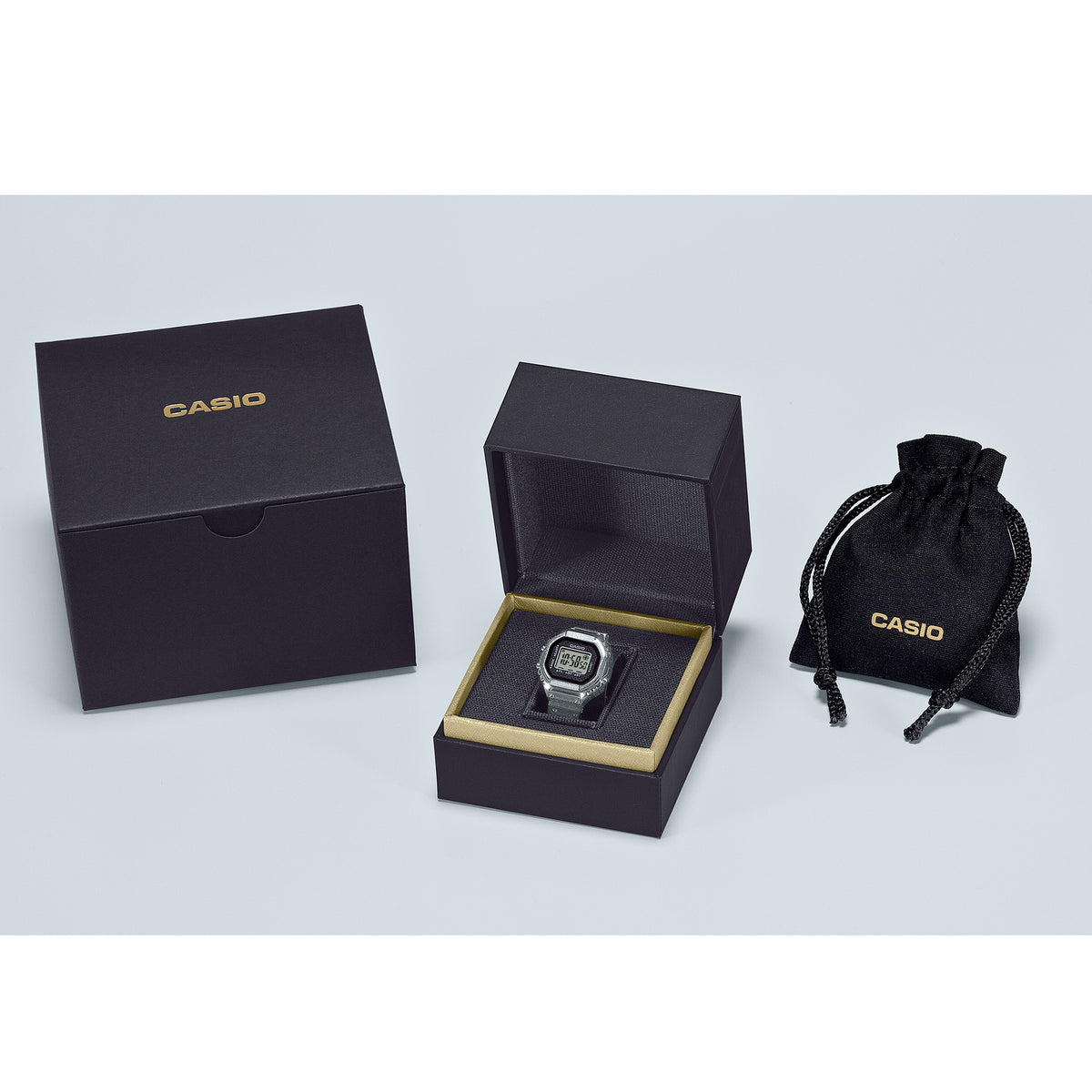 Front-on view of the Casio Ring Watch Digital 25mm Watch CRW001-1D in an open box with a closed box and pouch on a light gray background