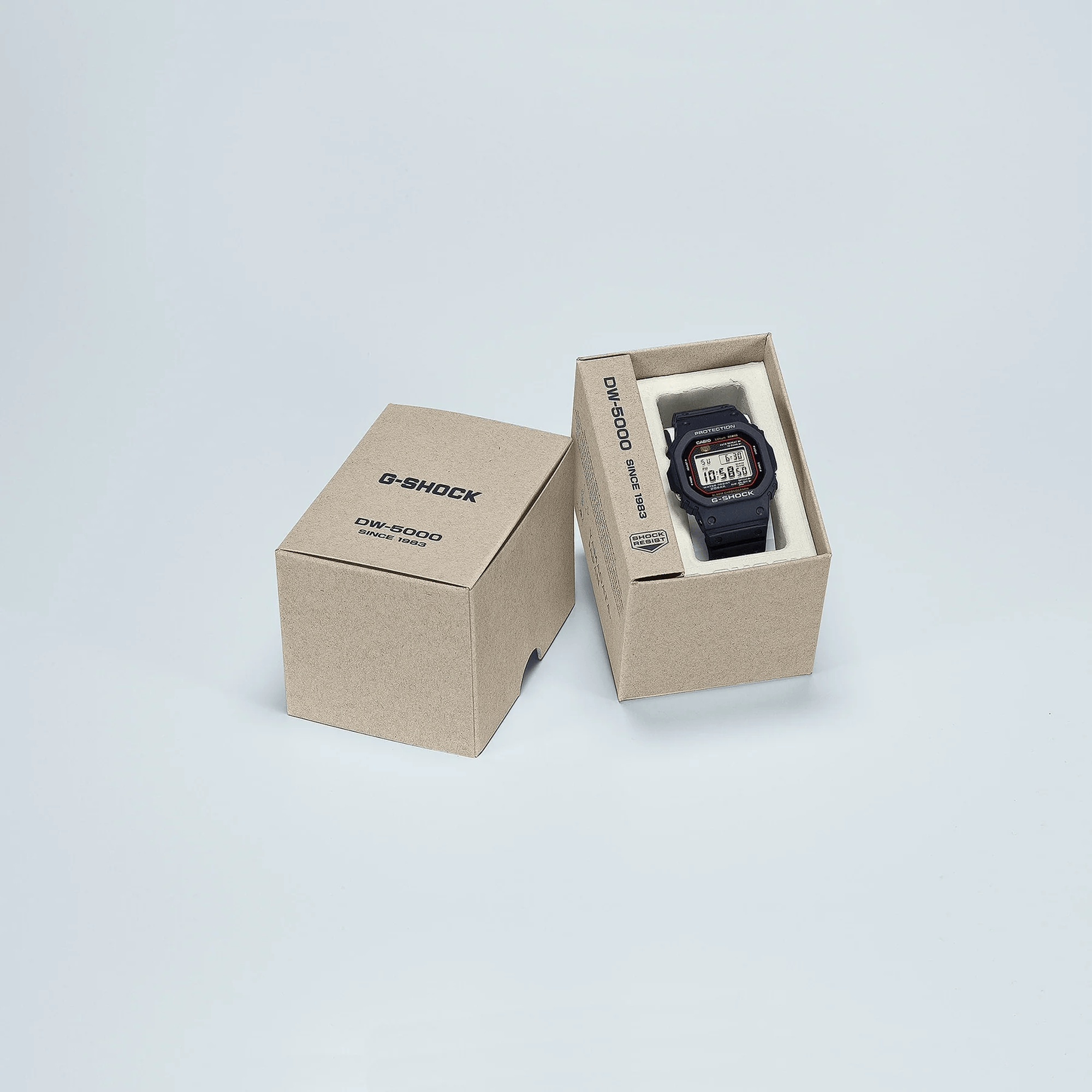 Casio G-SHOCK DW5000R-1A digital watch with stainless steel case, black resin band, screw back case, and classic square design in watch box
