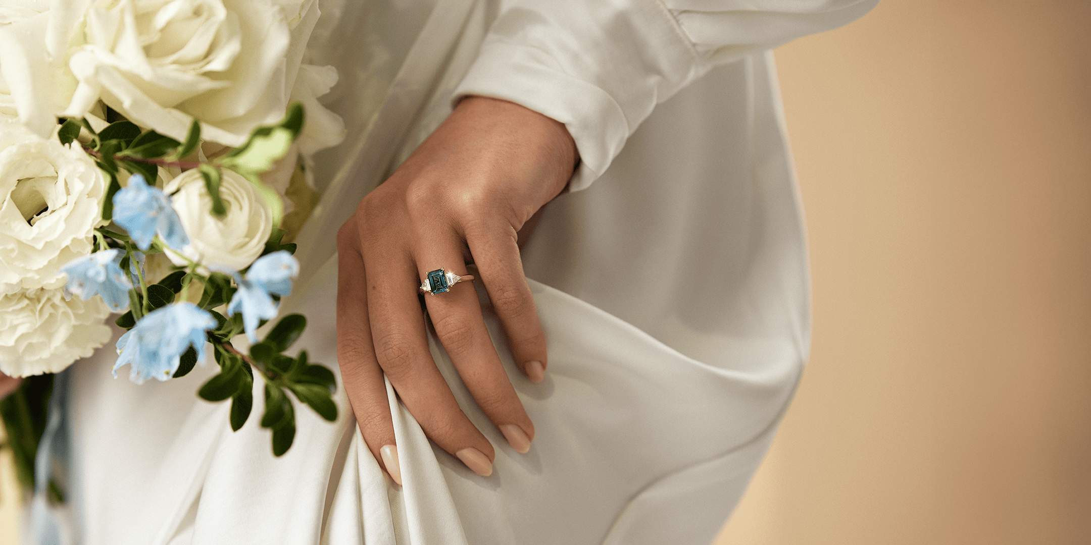 Close-up of a hand wearing a ring with blue gemstones and diamonds