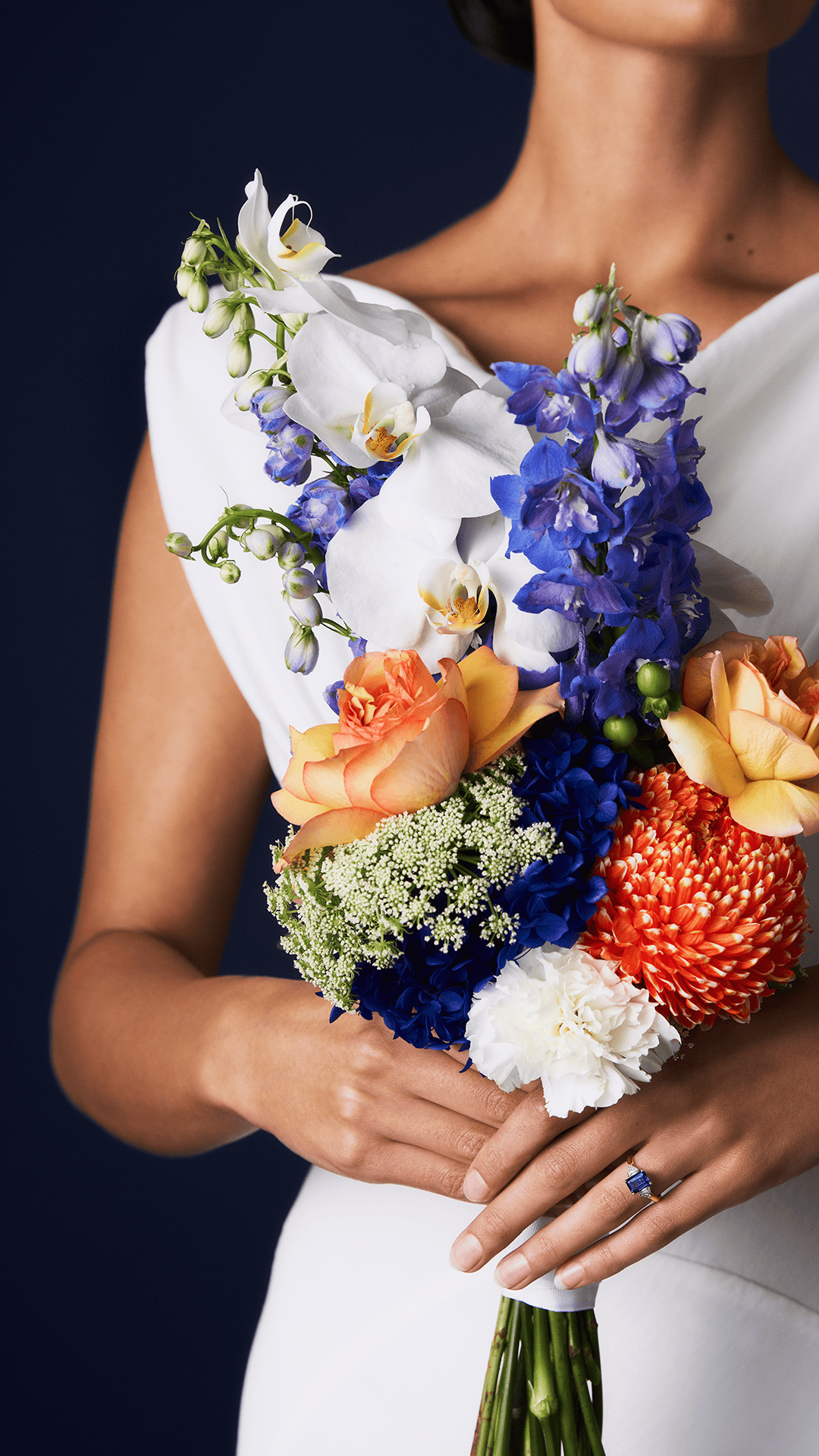 Bouquet of colorful flowers held by a person wearing a blue gemstone ring