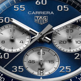 TAG Heuer Carrera Chronograph Sport CDB2111.BA0054 captured in extreme close-up on the deep blue circular-brushed dial, highlighting the silver numerals and Super-LumiNova-treated hands. The silver azuré counters sit against the blue dial surface.