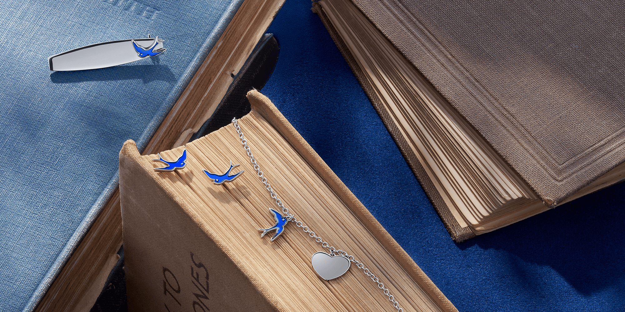 Blue bird-shaped earrings, brooch, and bracelet with a silver heart pendant