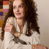 The Daniel Wellington Corta Grain-Link Women’s 24mm Quartz Watch DW00100993 worn on the wrist to show its petite size and fit. The compact gold cushion case and grain-link bracelet sit neatly on smaller wrists.
