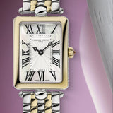 A close-up studio shot of a Frederique Constant wristwatch with a rectangular two-tone metal case and bracelet. The watch features a white mother-of-pearl dial with black Roman numerals and a gold crown.