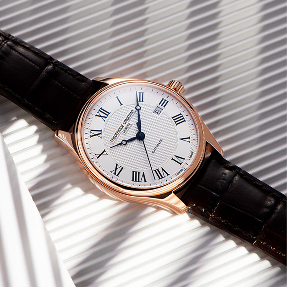 Frederique Constant Men's 40mm Stainless Steel Automatic Watch FC-303MC5B4 styled in a lifestyle setting, reflecting its refined, versatile design suited to both business and formal occasions. The white guilloché dial and rose gold-tone case complement a classic, polished look.