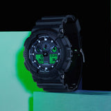 Casio G-Shock GA100BEG-1A front view showcasing the 55mm x 51.2mm black resin case with centre analogue display flanked by four large digital LCD windows with electro green printed accents, large aluminium hands, and the GA-100's signature oversized bold silhouette.