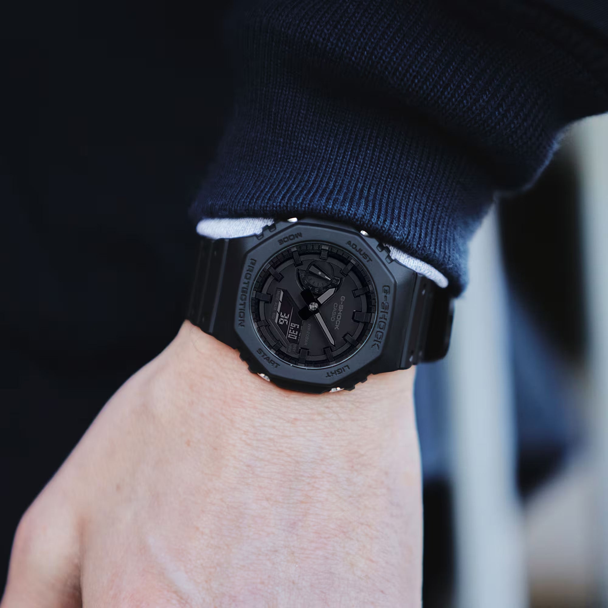 Casio G-Shock GA-2100-1A1 watch front view, featuring a 45.4mm all-black octagonal resin case with Carbon Core Guard construction, clean monochromatic analogue-digital dial with Arabic numeral indices, inverted LCD display, and distinctive integrated band design.