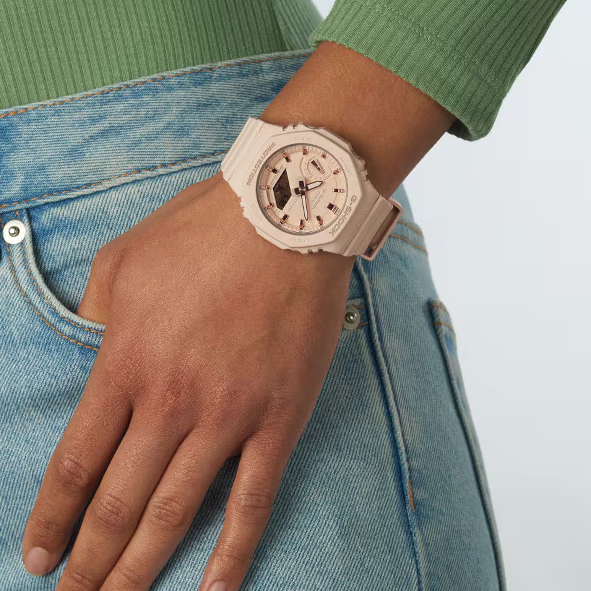 Casio G-Shock GMAS2100-4A watch front view, featuring a 46.2mm blush pink octagonal Carbon Core Guard resin case with a flat dial, rose gold-toned mirror bar indices, analogue hands with Neobrite lume, day sub-dial at 9 o'clock, and lower digital LCD display window - showcased on wrist