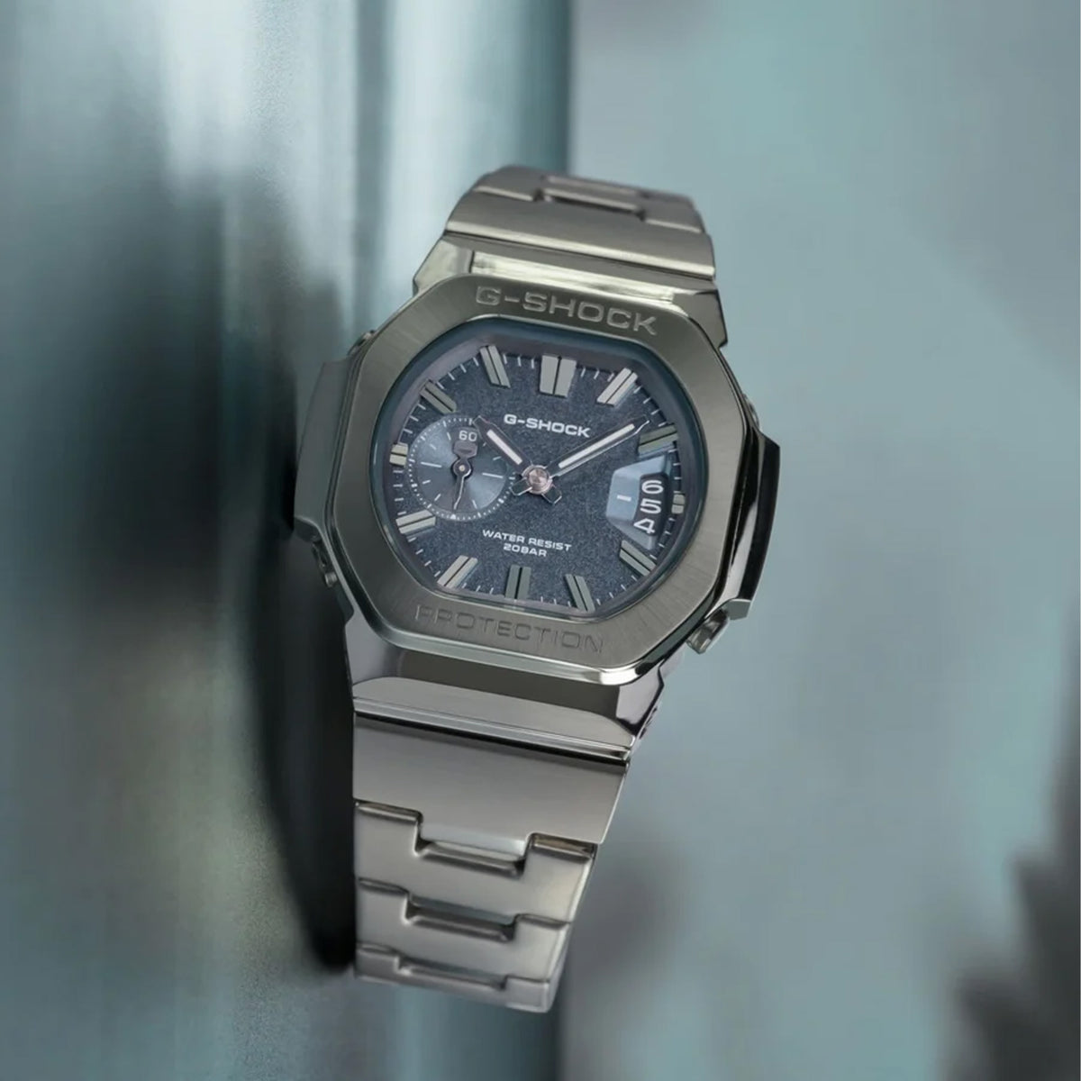 Three-quarter angle view of the Casio G-SHOCK 2500 Series Quartz Men’s Watch GMC2500D-1A2, 46.7mm case, highlighting the silver bezel and rounded octagonal case. The blue dial and bar indexes are visible.