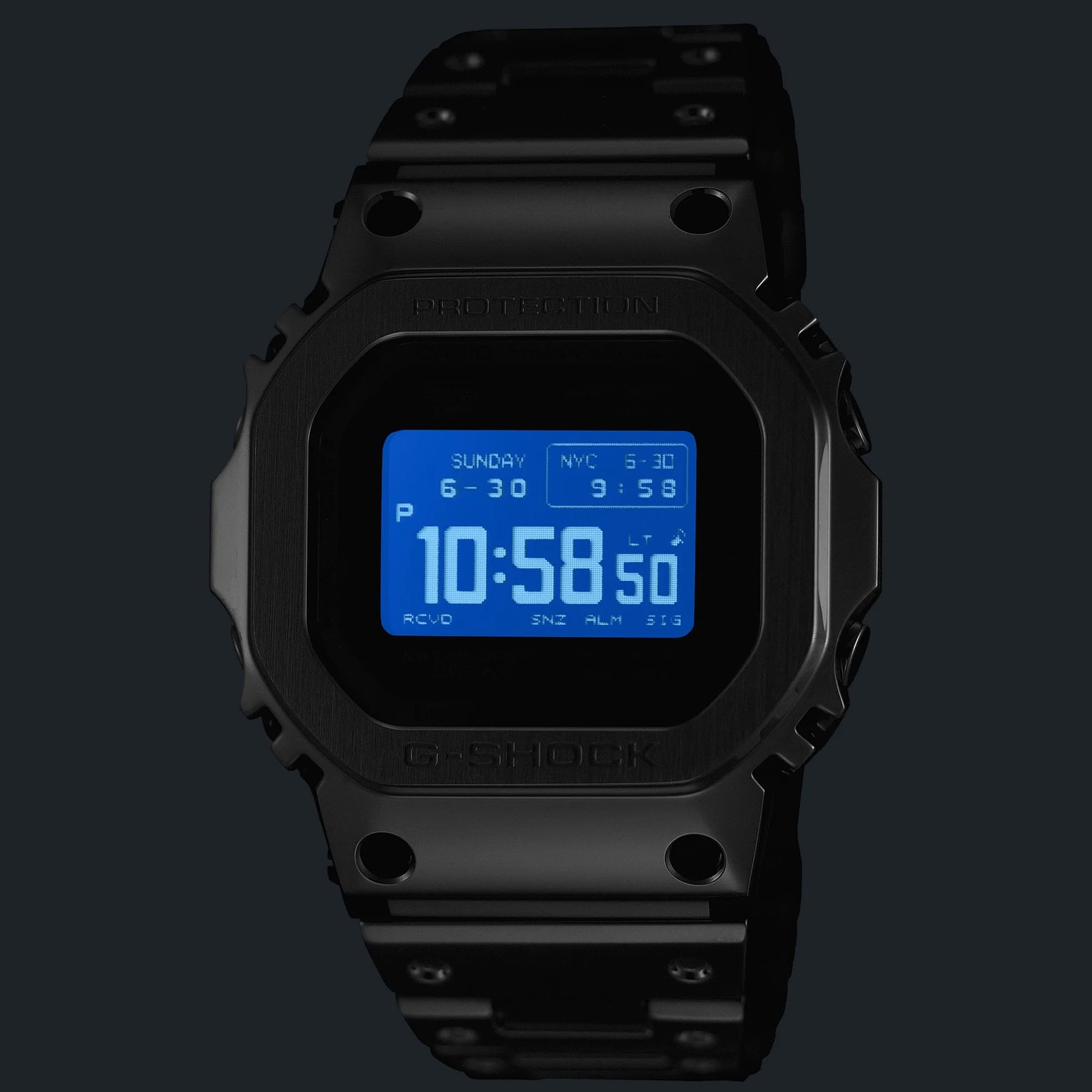 The Casio G-Shock Digital Watch GMWBZ5000BD-1D photographed in low light with the Super Illuminator LED backlight activated, showing the all-black ion-plated full-metal case glowing with bright LED illumination across the MIP LCD display — outstanding night-time readability in a dramatic all-black form.