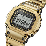 Three-quarter angle view of the Casio G-SHOCK Full Metal GMW-B5000GD-9 Men's Digital Watch, 49mm case, highlighting the forged and polished gold-tone stainless steel bezel. The black digital display and dial detailing are visible from this angle.