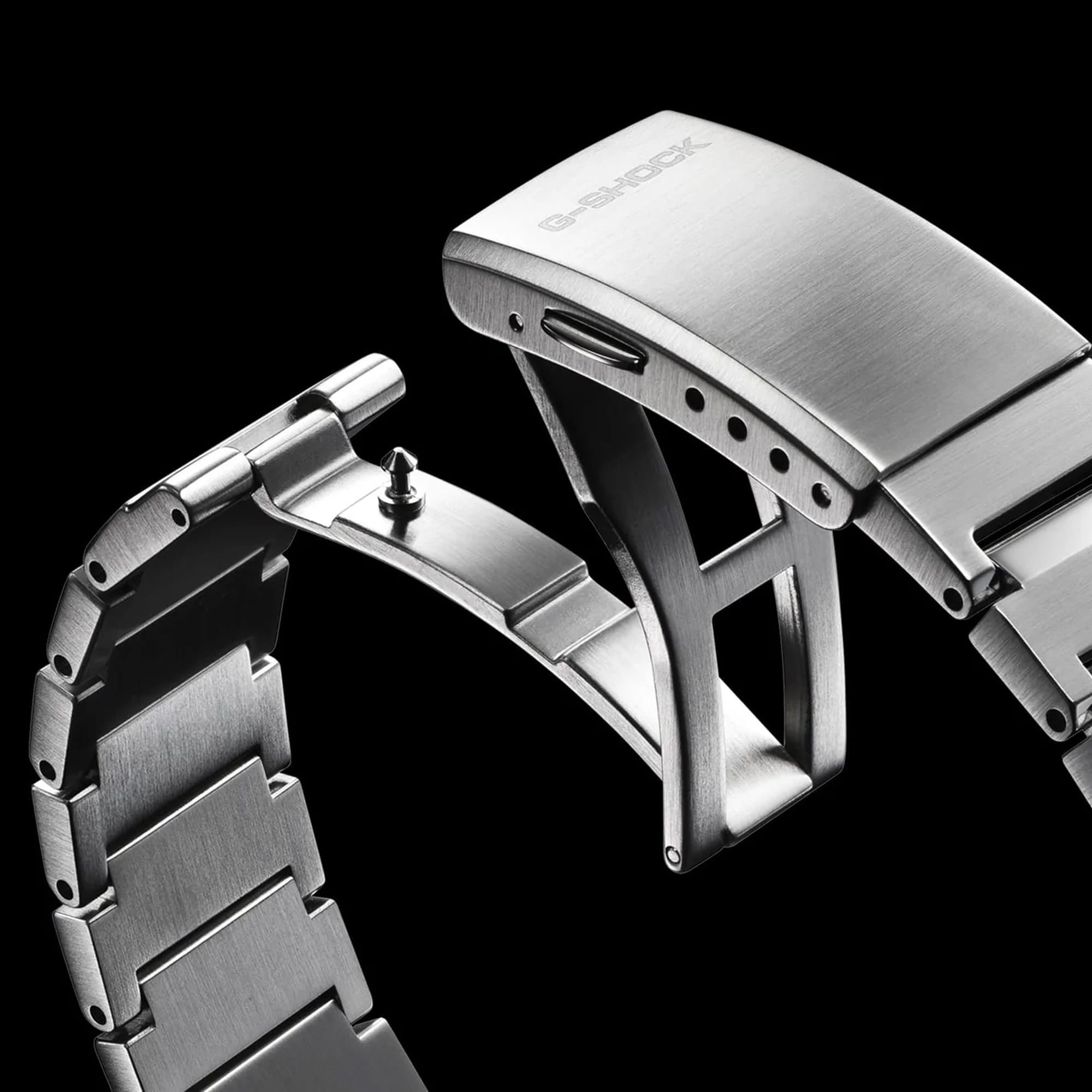Close-up of a silver watch strap with 'G-Shock' branding on a black background