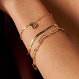 Woman wearing a 9ct yellow gold herringbone bracelet layered with gold bracelets