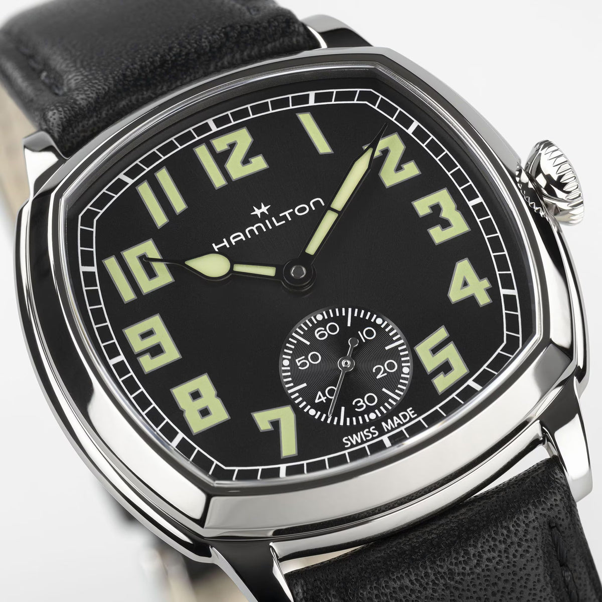 Hamilton American Classic Cushion Mechanical Unisex 34mm Watch H36129730 is shown in close up, revealing the square-style numerals, railway minute track and small seconds sub-dial. The slim hands stand out against the black dial.
