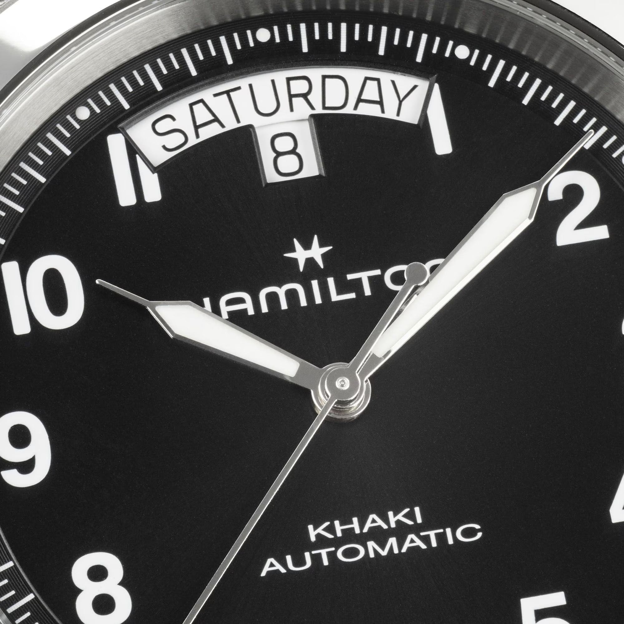 Close-up of Hamilton Khaki Field King H64475531 black dial showing bold Arabic numerals, luminous syringe hands, and curved day-date window at 12 o'clock
