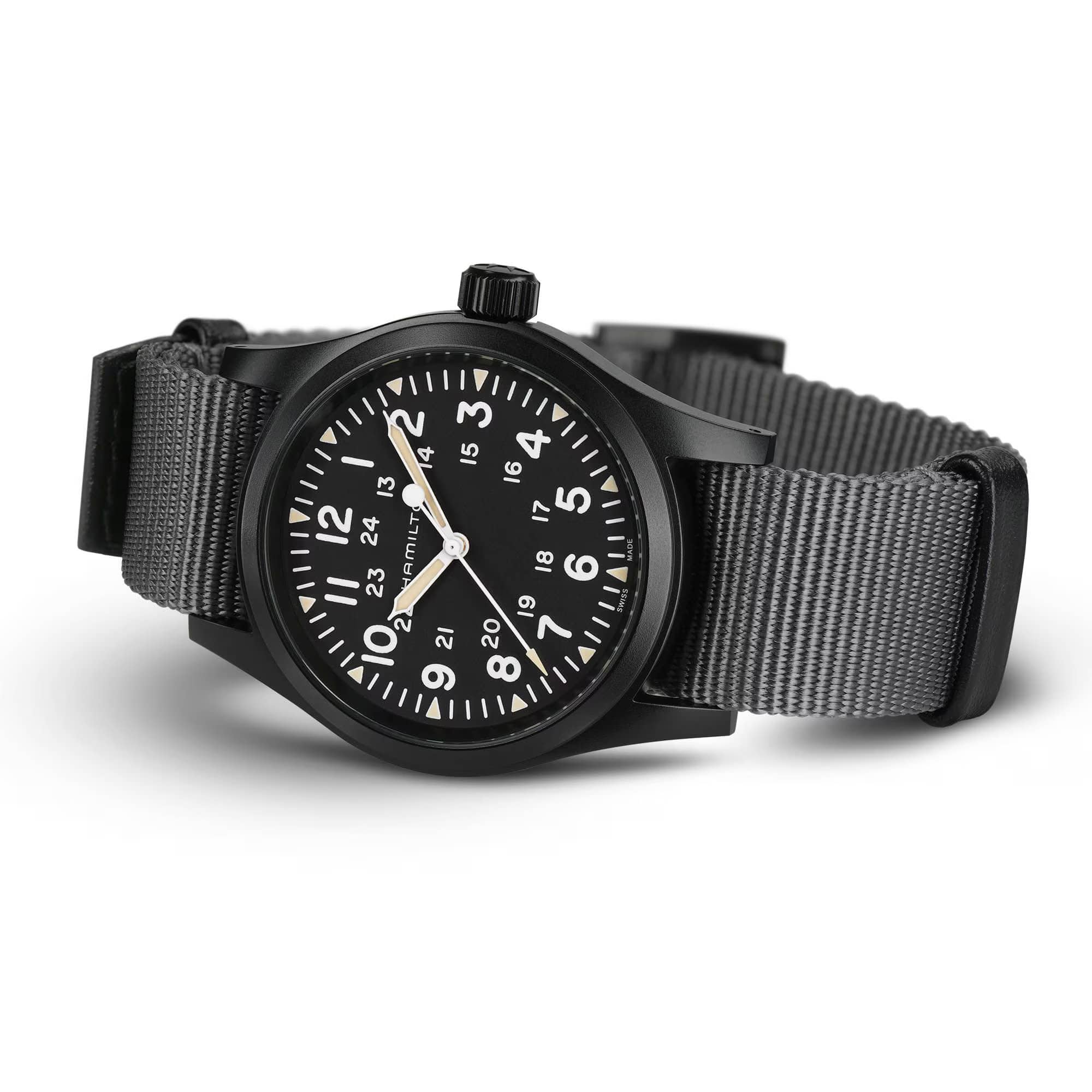 Hamilton Khaki Field Mechanical 38mm Watch H69409930 is shown at a 3/4 angle, highlighting the sapphire crystal, black dial, and NATO strap together. The angle showcases the watch's faithful recreation of its 1960s military field watch origins.