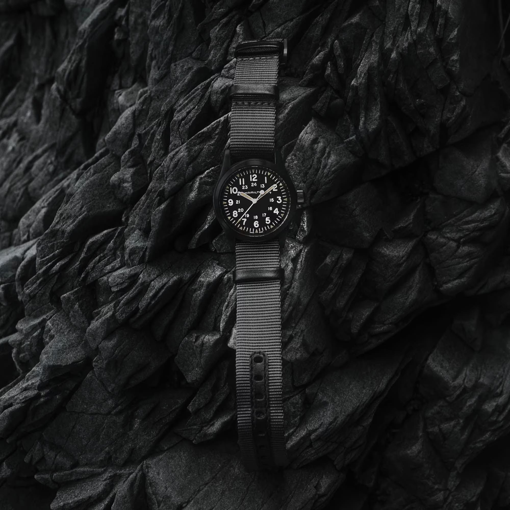 Hamilton Khaki Field Mechanical 38mm Watch H69409930 is shown at a 3/4 angle, highlighting the sapphire crystal, black dial, and NATO strap together. The angle showcases the watch's faithful recreation of its 1960s military field watch origins.