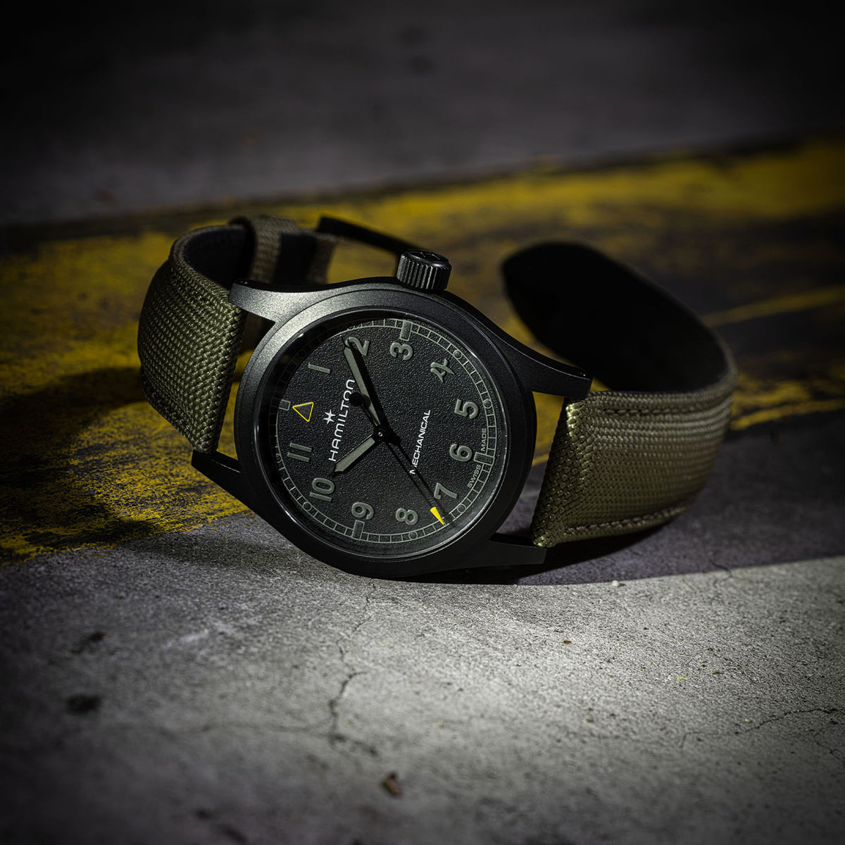 Hamilton x Call of Duty Khaki Field Mechanical Men’s 38mm Watch H69469930 is shown from the side, displaying the sandblasted black PVD case and crown. The khaki green fabric strap runs through the fixed lugs.