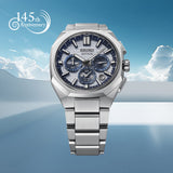 From this angle, the light silver dial's blue accents and symmetrical sub-dial layout are visible alongside the faceted bezel. The easy-adjust three-fold clasp with push-button release is set into the bracelet's closure.