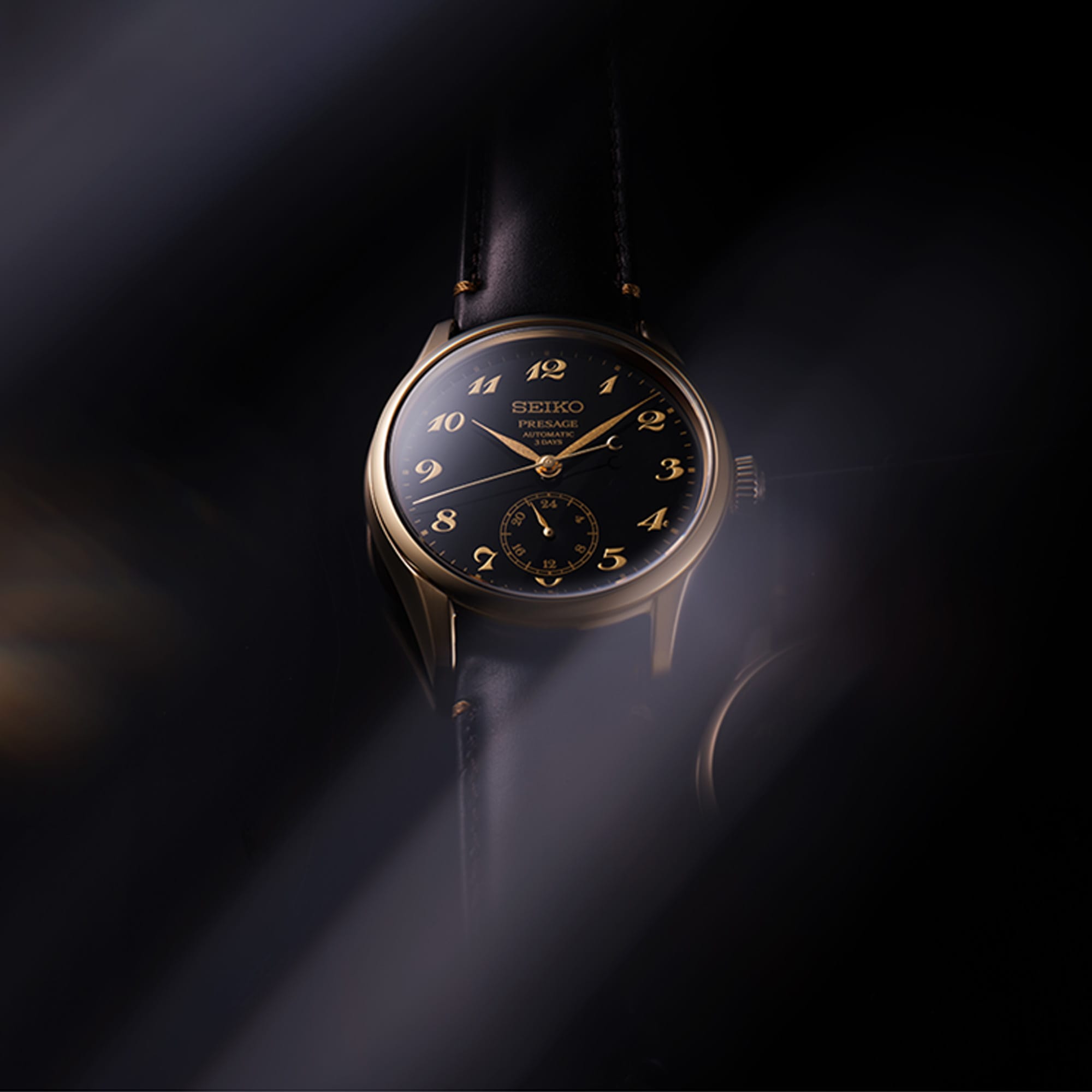 The Seiko Presage wristwatch with a black dial, gold-tone numerals and hands, and a bronze-toned case, shown against a dark moody background with dramatic light beams.