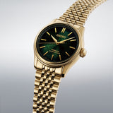 From this angle, the Seiko Presage Automatic 38mm Watch HCC009J shows the matsuba-iro dial's pine bark texture and gold-toned indexes together with the coin-edged bezel and gold-coloured case.