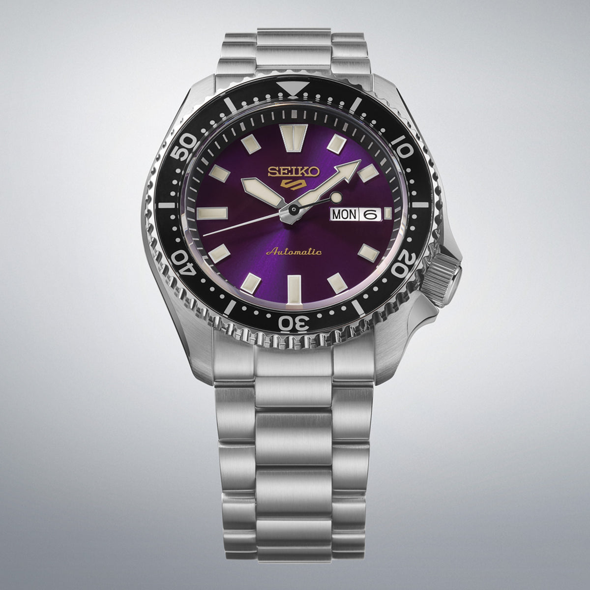 From this angle, the Seiko 5 Sports SKX Series Automatic Men's 42.50mm Watch HDB003K shows the Edo purple dial's gold logo and rotating bezel together with the stainless steel bracelet.