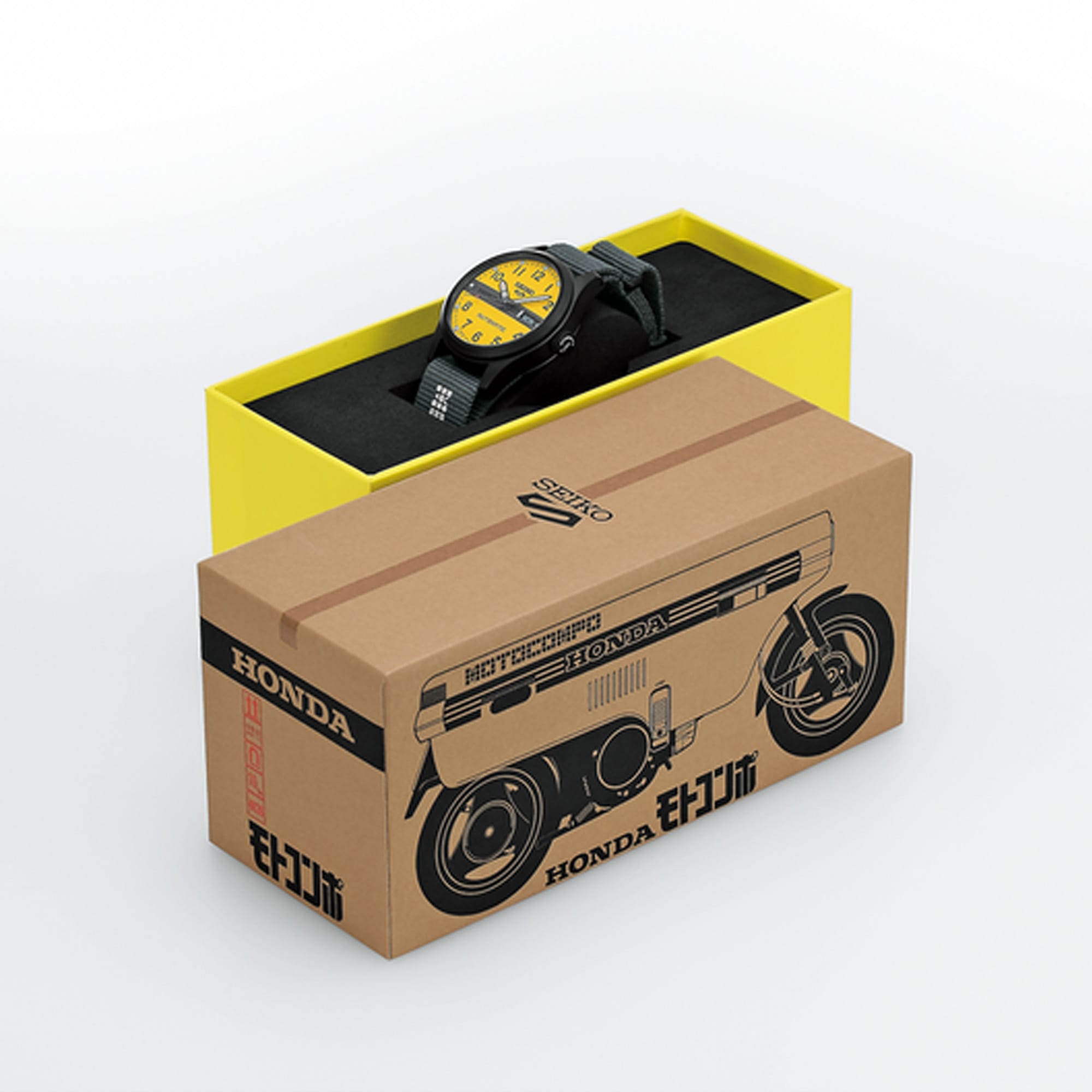 A Seiko 5 Automatic 36.40mm Watch HDB010K with a yellow dial sits inside a bright yellow box, with a large brown cardboard box printed with a motorcycle illustration and Honda branding in the foreground on a clean white background.