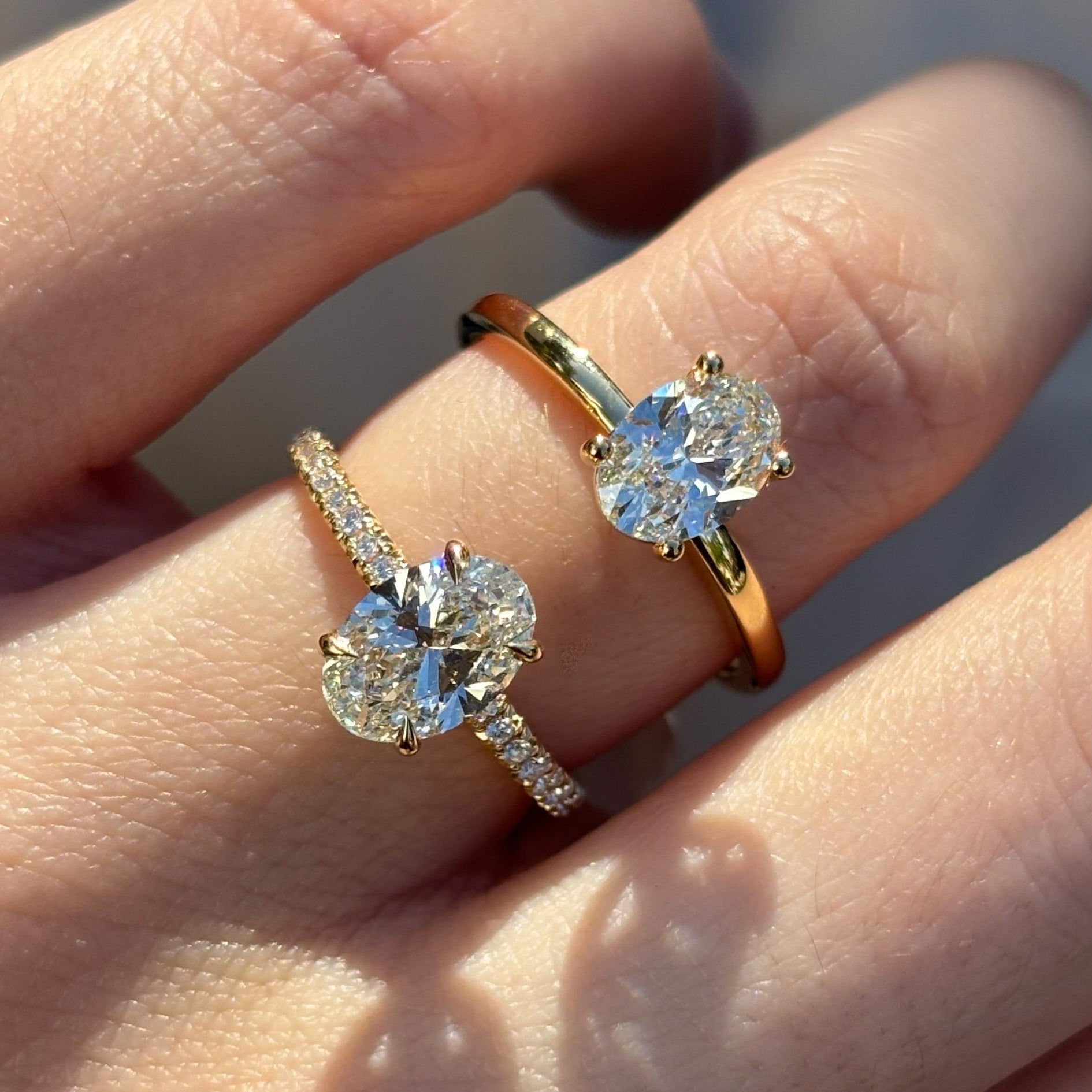 Two diamond oval rings on a person's finger