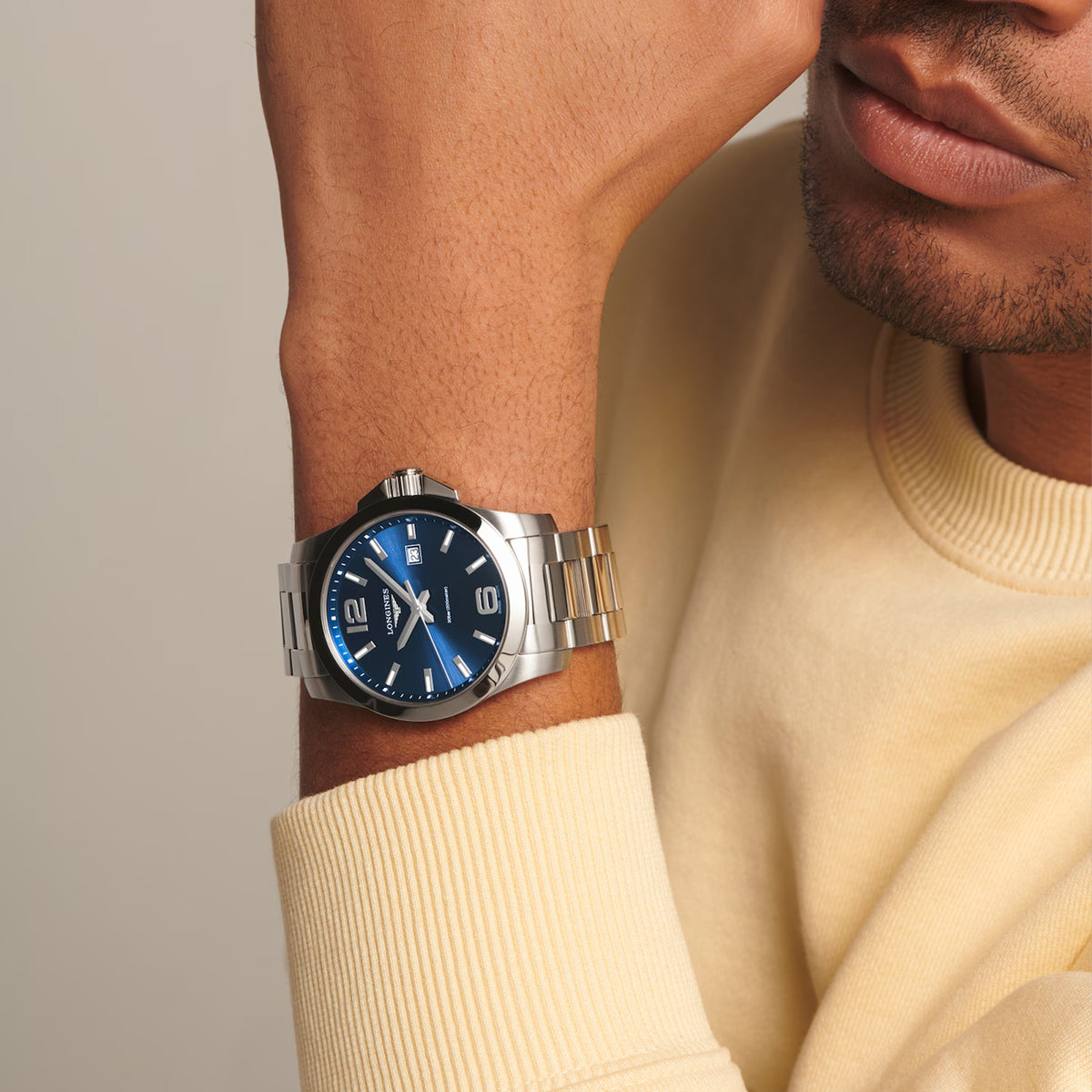 The Longines Conquest Men's 43mm Stainless Steel Quartz Watch L3.760.4.96.6 worn on the wrist, showing its sporty size and fit. The sunray blue dial and stainless steel bracelet give it a versatile look for both everyday and dressier outfits.