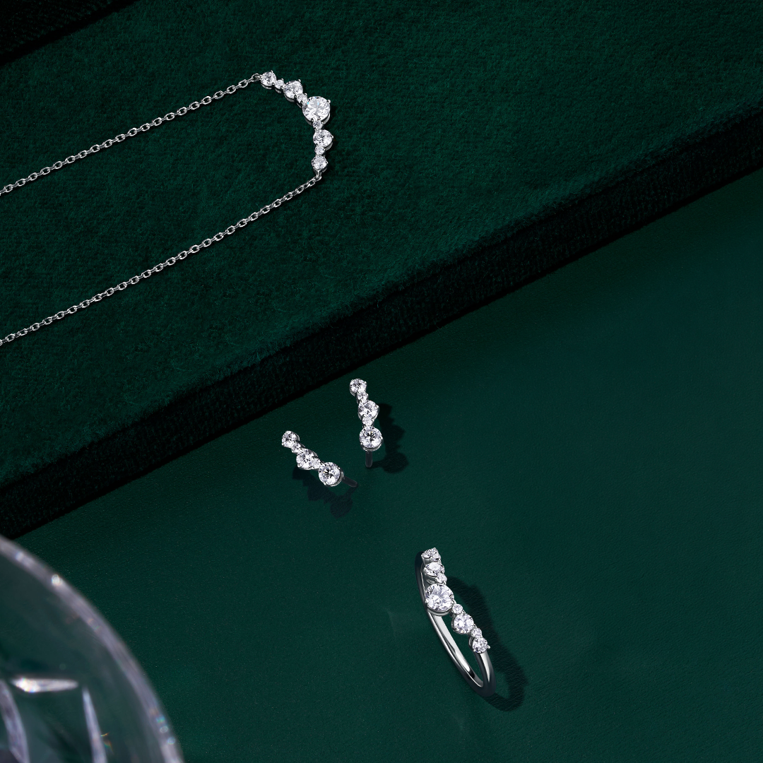 Front-on view of three Wallace Bishop 0.40 TDW Round Lab-Grown Diamond pieces in Sterling Silver: the Ring, reference LGRG040SSO, with nine claw-set diamonds in a chevron V shape on a smooth polished band, the Necklace, reference LGNK040SS, with a chevron-style row of claw-set diamonds on a 500mm (approximately 19.7 inch) cable chain, and the Climber Stud Earrings, reference LGER040SS, with five claw-set diamonds on each earring.