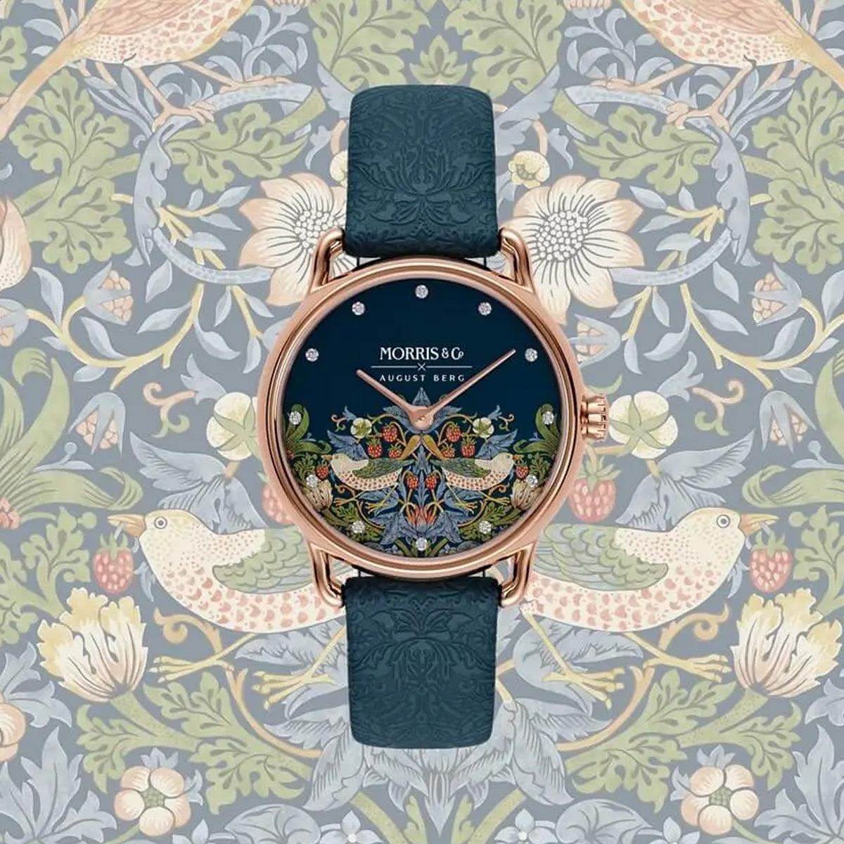 Morris & Co August Bera watch with a dark blue leather strap and a highly detailed, colorful peacock-themed dial, set against a William Morris-style floral and bird patterned background.