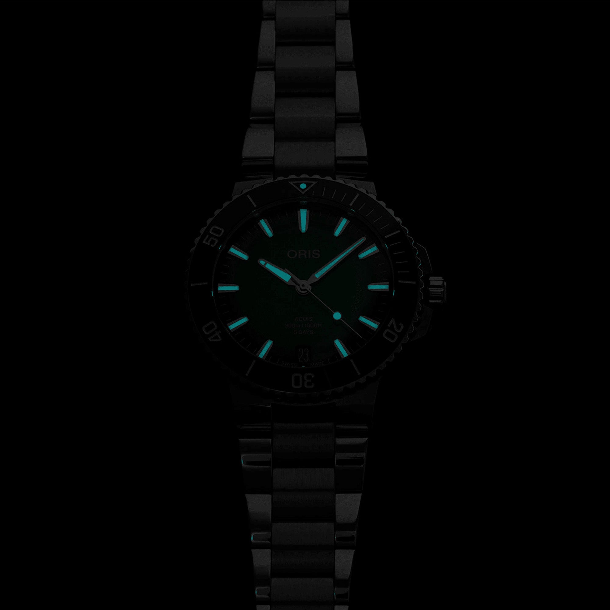 Close-up of Oris Aquis Calibre 400 green dial showing luminous hour markers in dark lightning