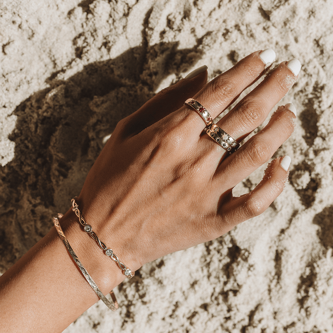 Hand with Three Gold and Gemstone Bands and two Gold Bracelets