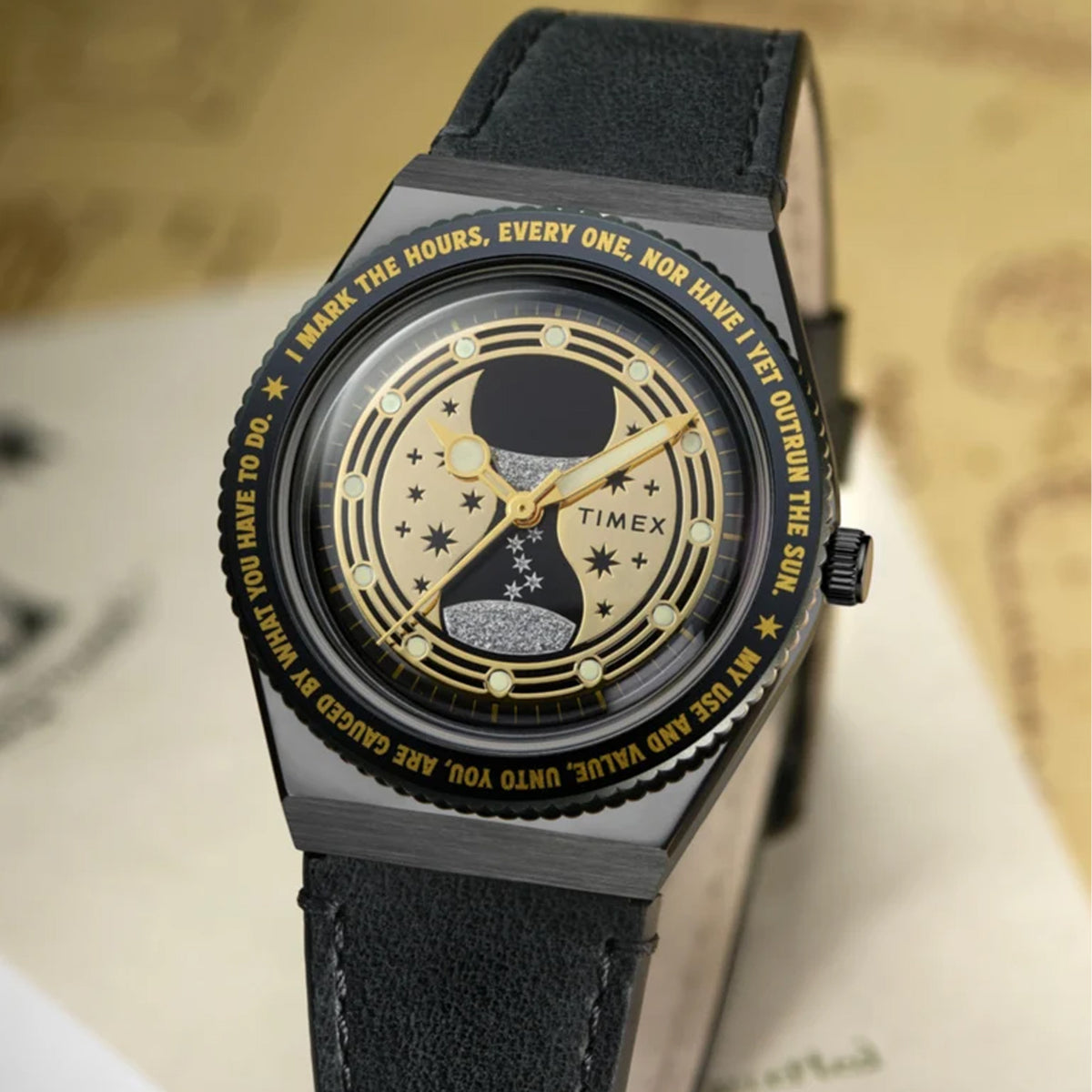 The Timex x Harry Potter Time Turner Quartz 36mm Watch TW2Y76000 is shown beside a gold Time-Turner pendant and Hogwarts-themed papers. The black strap and gold hourglass dial suit Harry Potter fans and collectors.