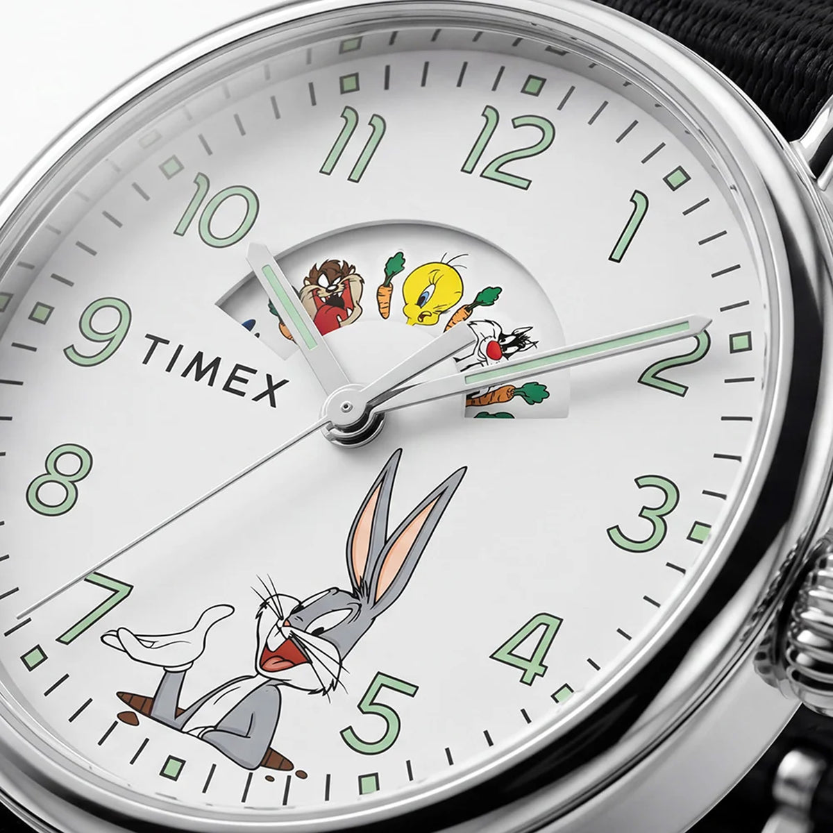 The Timex x Looney Tunes Weekender Quartz 40mm Watch TW2Y99100 has a white dial featuring Looney Tunes characters. The round silver-tone case frames the playful, nostalgic design.