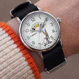 The Timex x Looney Tunes Weekender Quartz 40mm Watch TW2Y99100 pairs its silver-tone case with a black fabric strap on the wrist. The 40mm size gives it a relaxed, casual look.