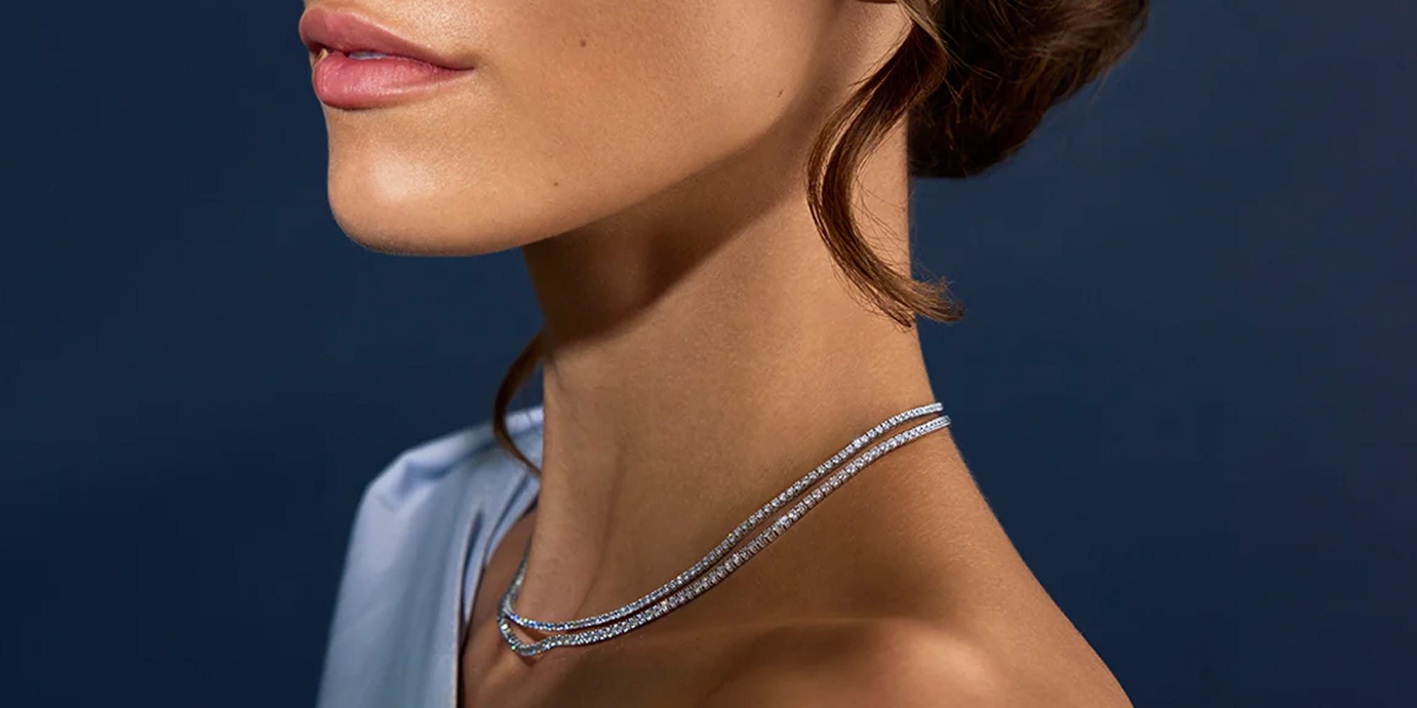 Woman wearing two diamond tennis necklaces on a neck