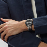 TAG Heuer Formula 1 Date WAZ2011.BA0842 shown worn on the wrist, illustrating the case proportions and steel bracelet fit. The grey dial stands out against the sleeve in frame.