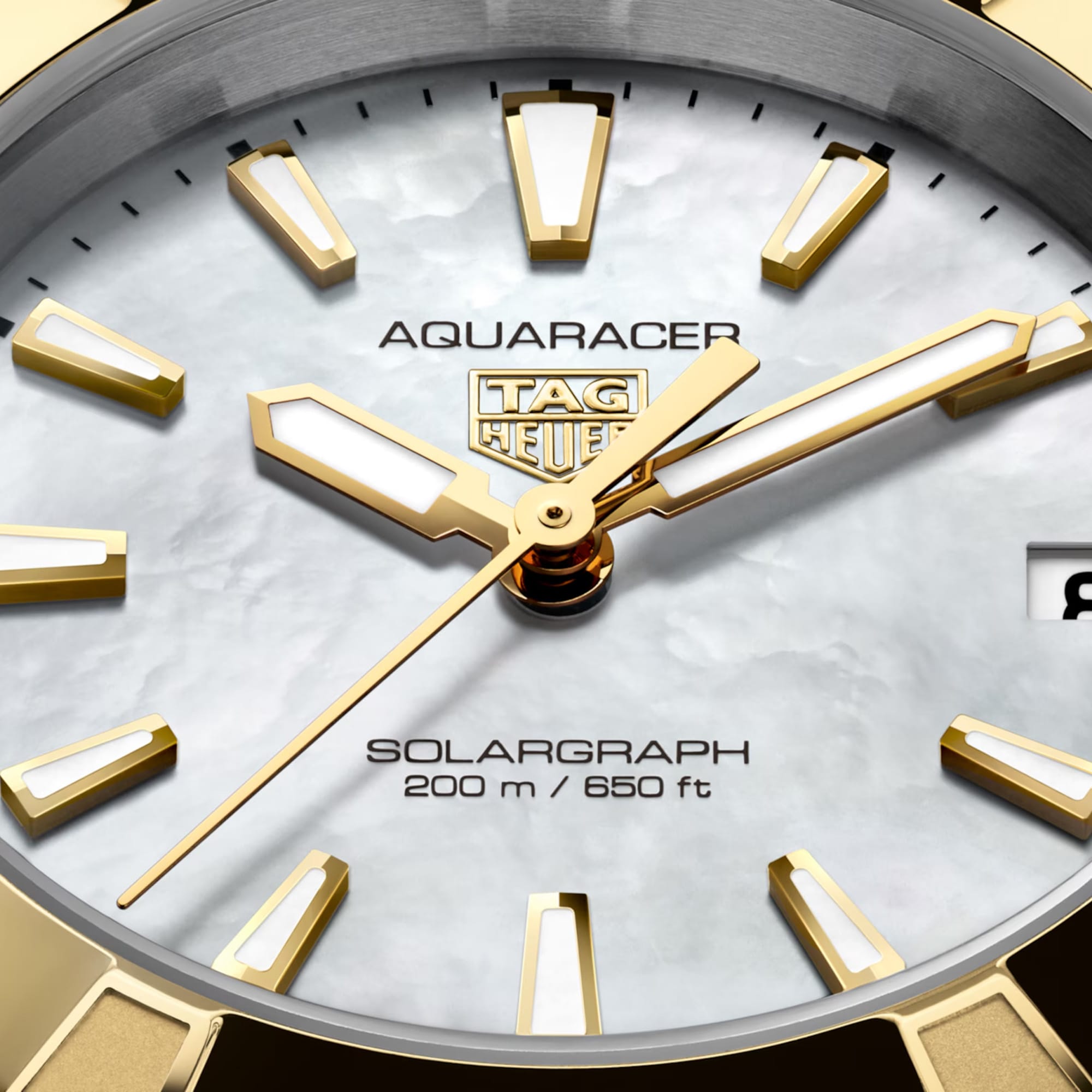 TAG Heuer Aquaracer Professional 200 Solargraph WBP1327.BB0004 captured in extreme close-up on the white mother-of-pearl dial, highlighting the gold-plated applied indexes and date window at 3 o'clock. The white Super-LumiNova hands sit against the pearlescent dial surface.